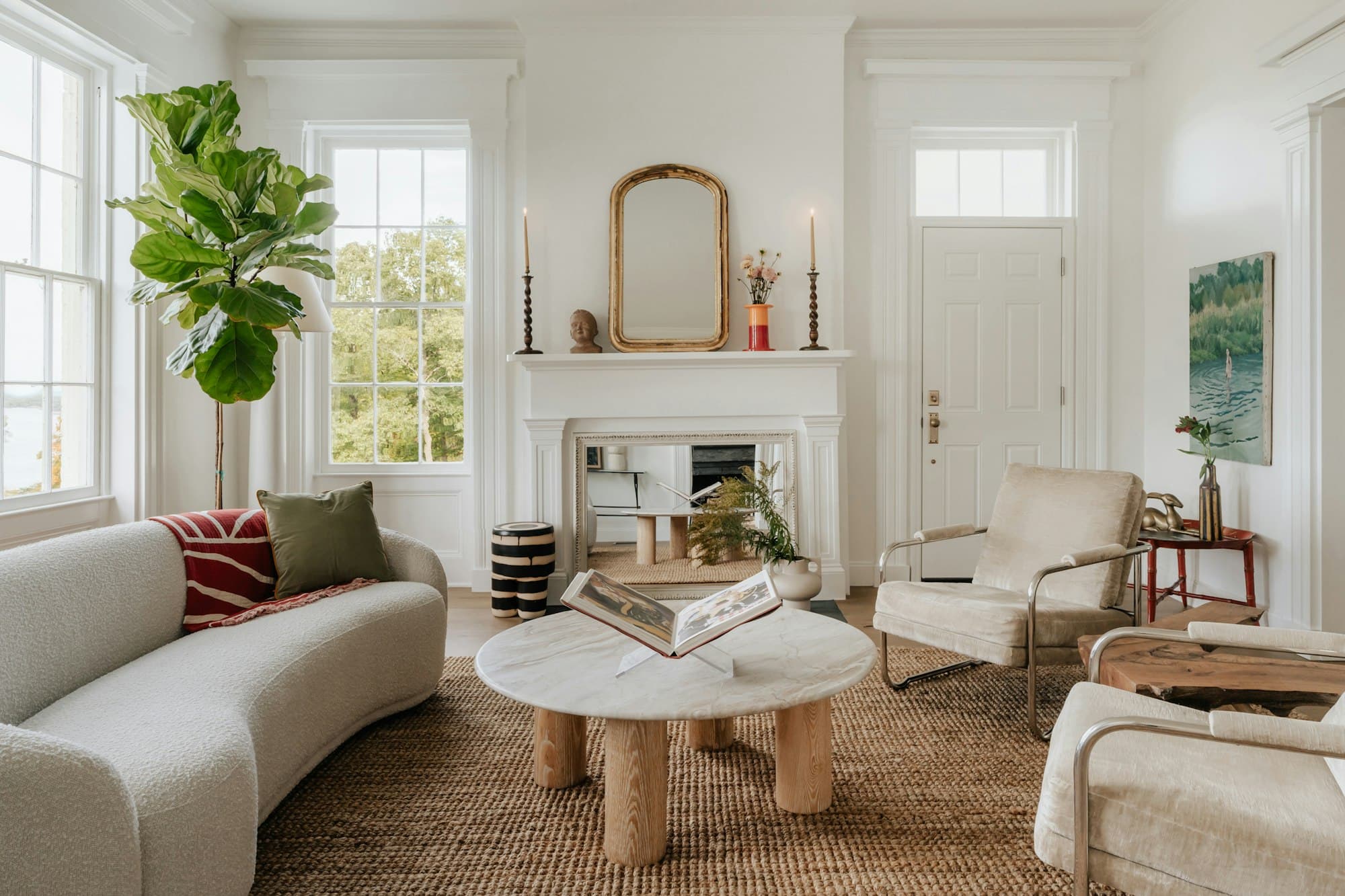 Sala de estar clara com lareira, janelas altas e sofá curvo
