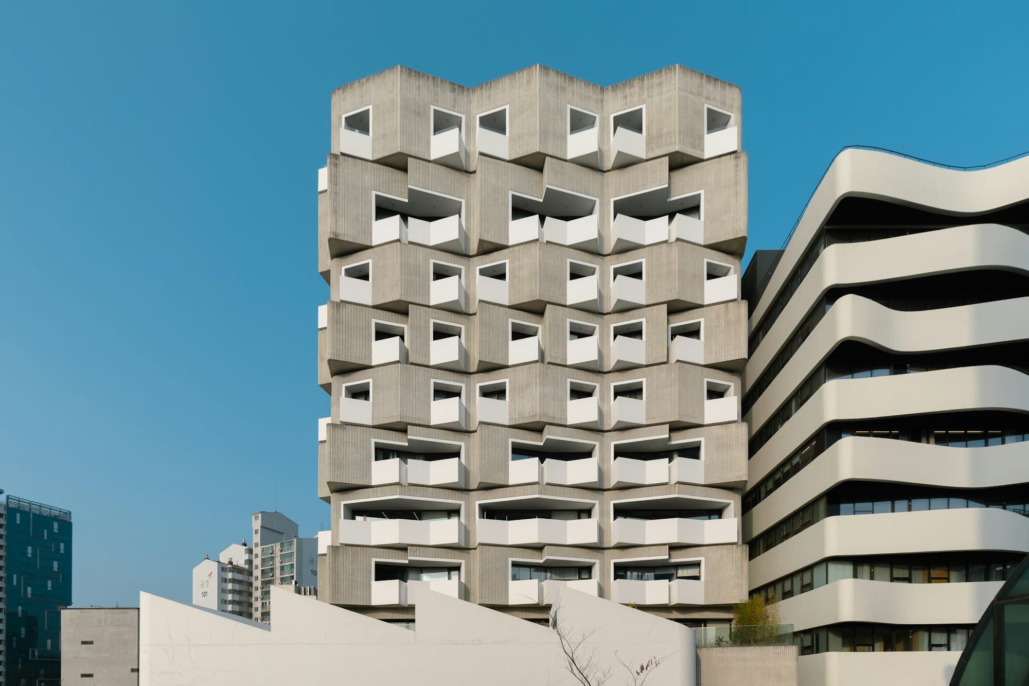 Edifício contemporâneo com fachada de concreto e sacadas recortadas