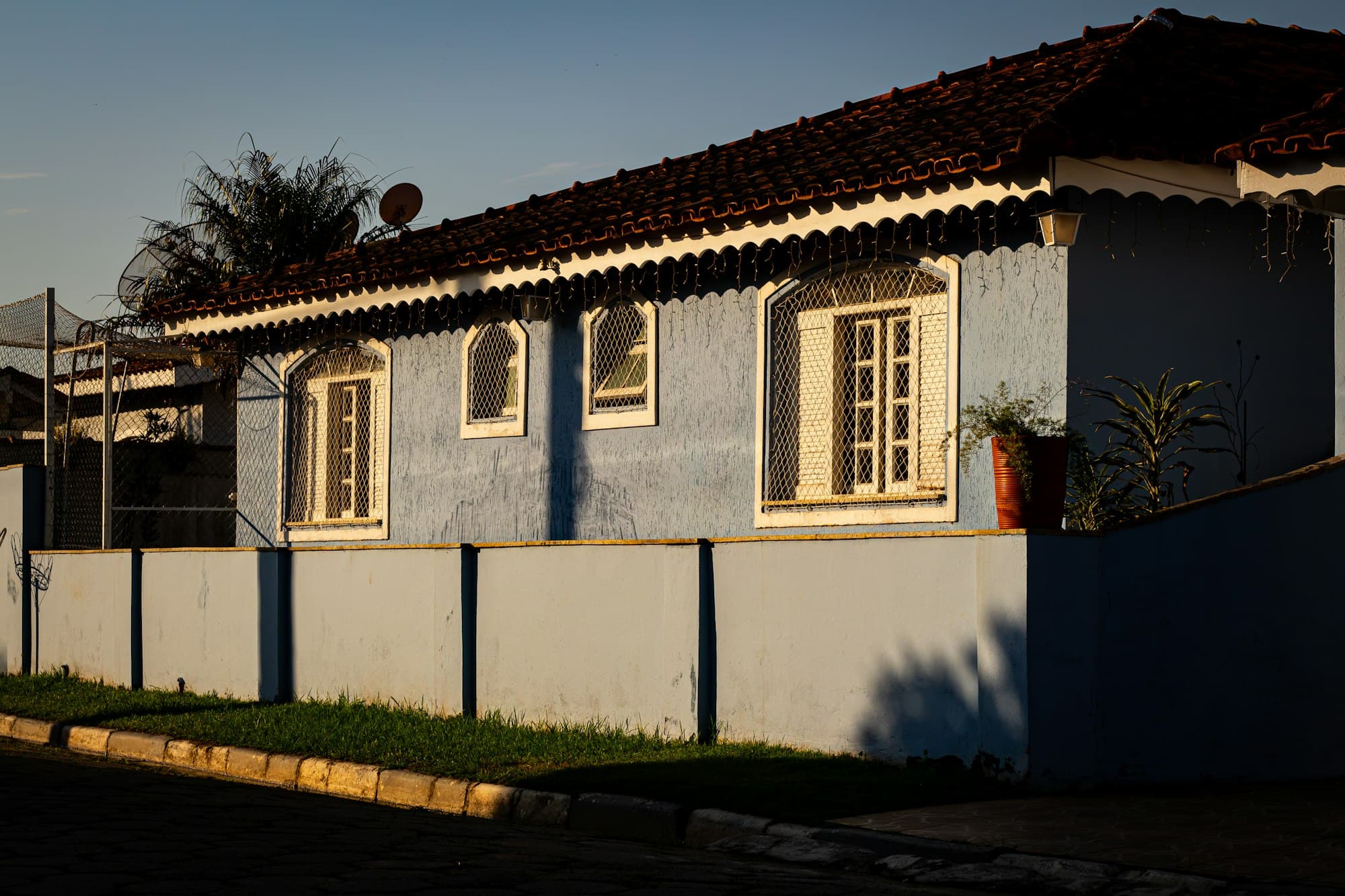 Fachada de casa pintada em azul com esquadrias escuras